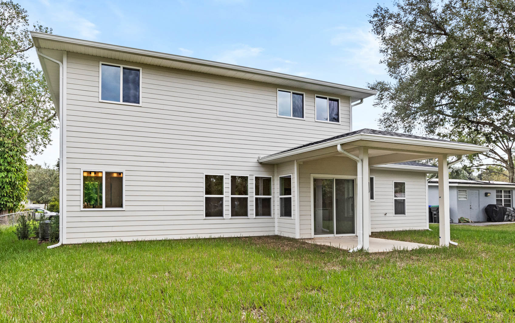 back of two story home with grass and trees